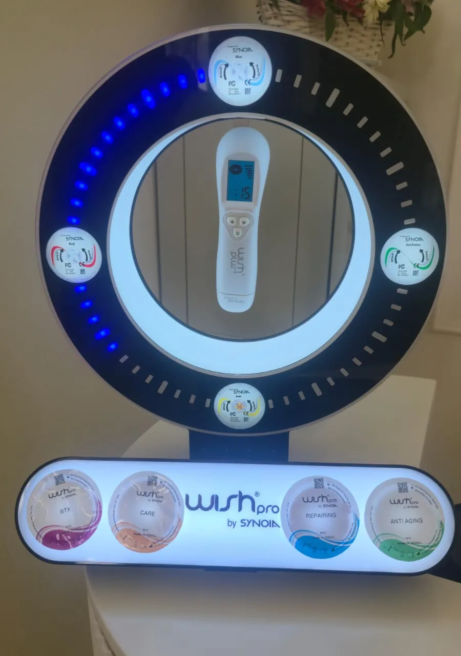 Urządzenie do infuzji magnetycznej WishPro Plus z okrągłym panelem podświetlanym diodami LED i zestawem kapsułek pielęgnacyjnych.